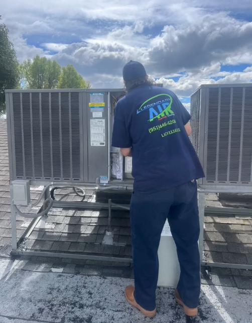 Rudy Vargas working on a commercial rooftop HVAC unit, showing the Legendary Air logo on his shirt